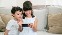 Dos niños con un dispositivo movil en sus manos