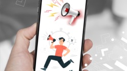 mano que sostiene un celular en cuya pantalla aparece la ilustración de una persona corriendo en medio de señales de emergencia.
